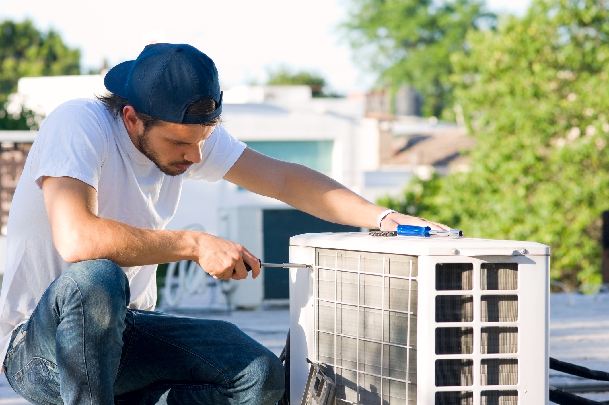 Serviceman inspecting a heat pump on a commercial roof