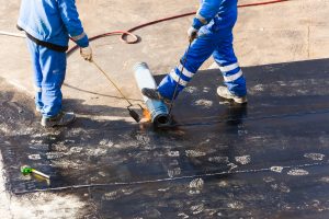 McDonald & Wetle employees install roofing material on a commercial building