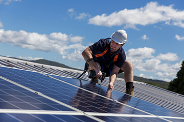 A man installs solar panels on a roof