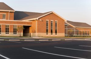 Large school building with parking lot in forefront