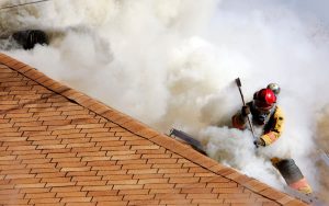 Firefighter on roof of building with smoke