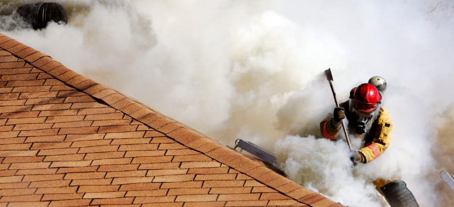 Firefighter on roof of building with smoke