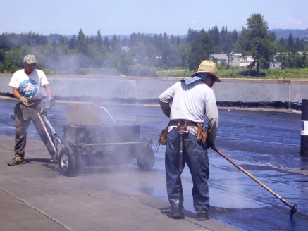 McDonald & Wetle employees spread bitumen on a commercial roof