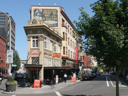 A large building houses a bar and a hotel  on a city corner